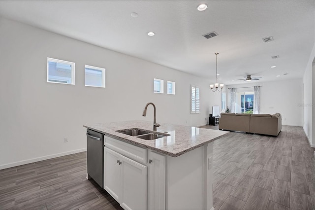 kitchen featuring pendant lighting, sink, dishwasher, white cabinetry, and light stone countertops