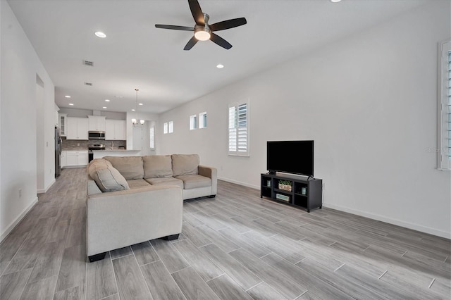 living room with ceiling fan with notable chandelier