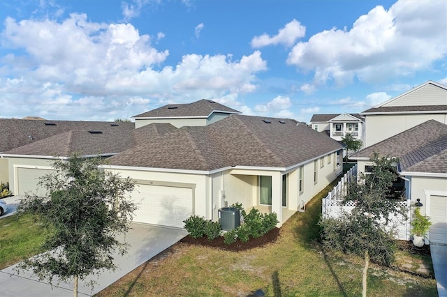 exterior space with a garage, central AC unit, and a front lawn