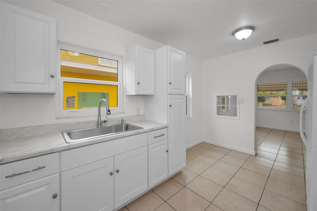 kitchen featuring sink, light tile patterned floors, white cabinetry, white refrigerator, and light stone countertops