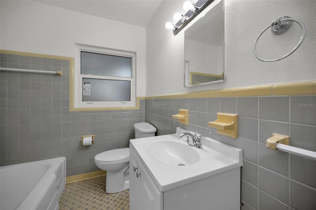 bathroom featuring vanity, a tub to relax in, tile walls, and toilet