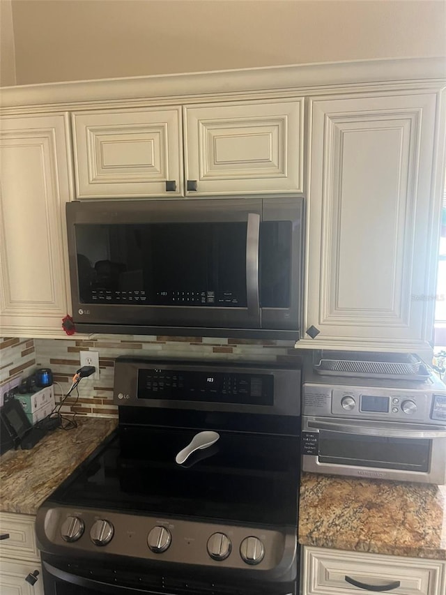 kitchen featuring stainless steel electric range oven, white cabinets, light stone counters, and decorative backsplash