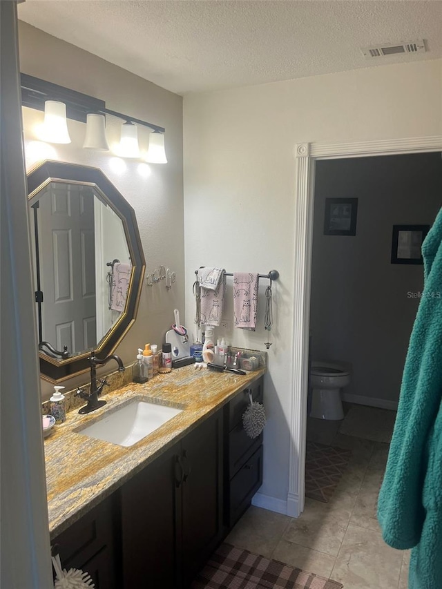 bathroom featuring vanity, a textured ceiling, and toilet