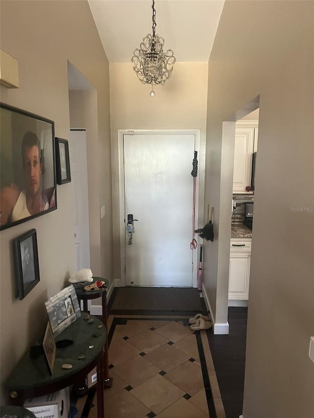 entryway featuring an inviting chandelier and dark tile patterned floors