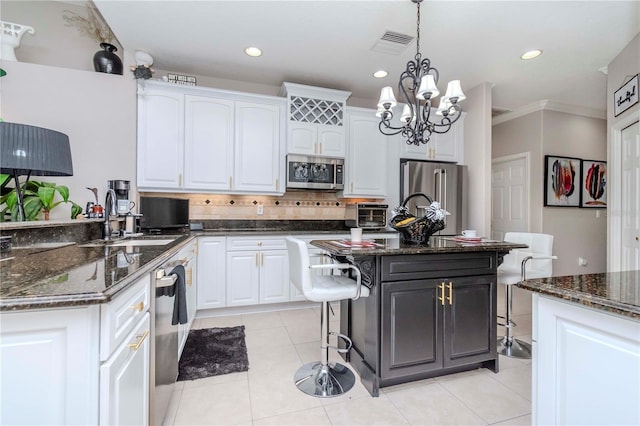 kitchen with a kitchen island, white cabinetry, appliances with stainless steel finishes, and pendant lighting