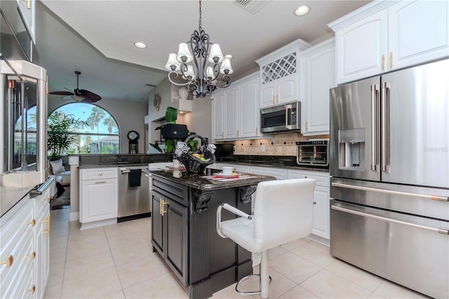 kitchen featuring dark stone countertops, a kitchen island, white cabinets, and appliances with stainless steel finishes