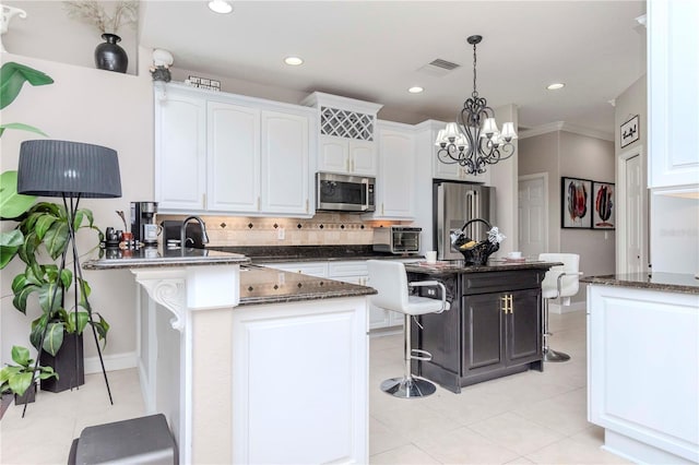 kitchen with a kitchen island, decorative light fixtures, white cabinets, a kitchen breakfast bar, and stainless steel appliances