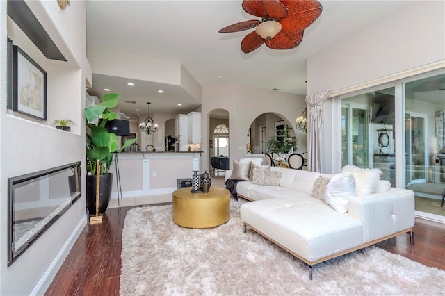 living room featuring dark hardwood / wood-style flooring, ceiling fan with notable chandelier, and vaulted ceiling