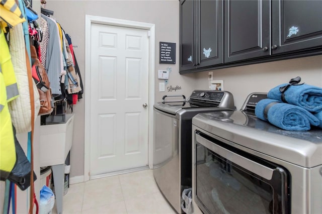 clothes washing area with cabinets, separate washer and dryer, and light tile patterned floors