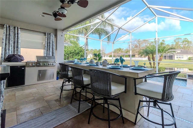 view of patio with an outdoor bar, ceiling fan, glass enclosure, area for grilling, and exterior kitchen