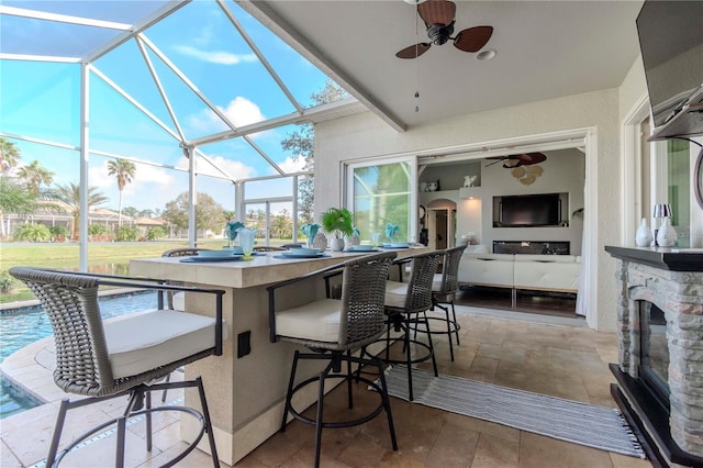 exterior space featuring ceiling fan, glass enclosure, and a bar