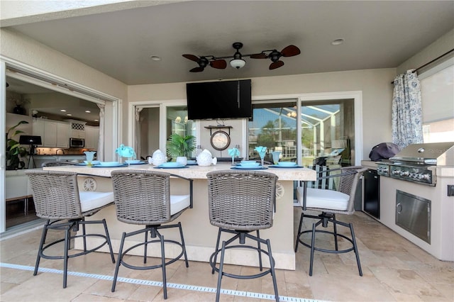 view of patio / terrace with exterior kitchen, area for grilling, an outdoor bar, and ceiling fan