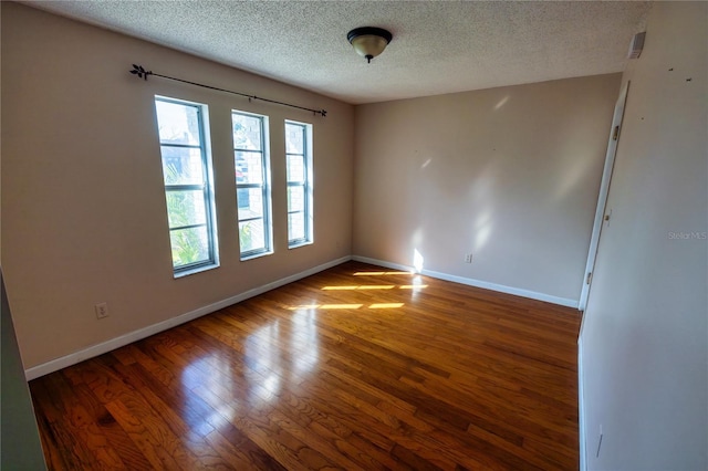 unfurnished room with dark wood-type flooring and a textured ceiling