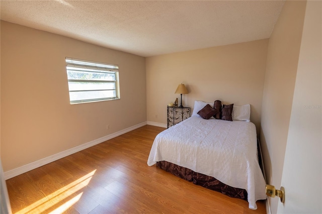 bedroom with hardwood / wood-style floors and a textured ceiling