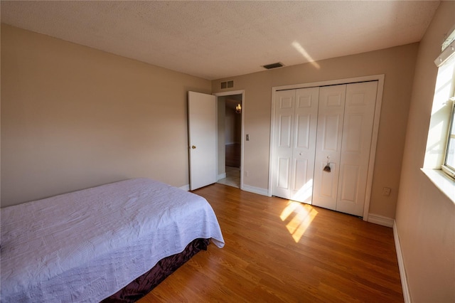 bedroom with hardwood / wood-style floors, a closet, and a textured ceiling