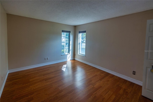 empty room featuring dark wood-type flooring and a textured ceiling