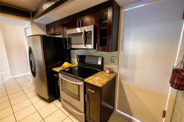 kitchen featuring light tile patterned flooring, dark brown cabinetry, light stone counters, appliances with stainless steel finishes, and backsplash