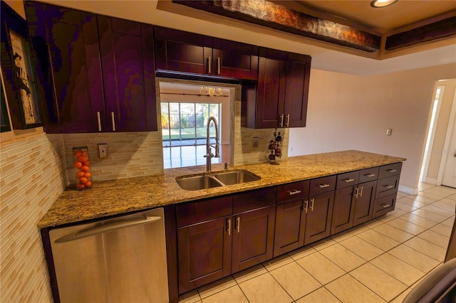 kitchen with sink, stainless steel dishwasher, a tray ceiling, light stone countertops, and backsplash