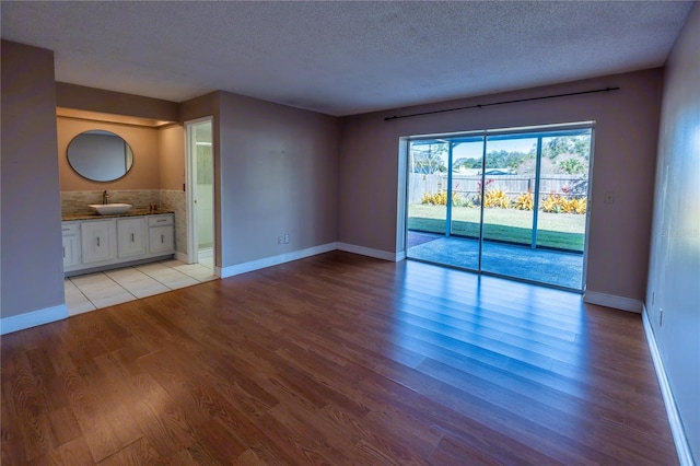 unfurnished living room featuring sink, a textured ceiling, and light wood-type flooring