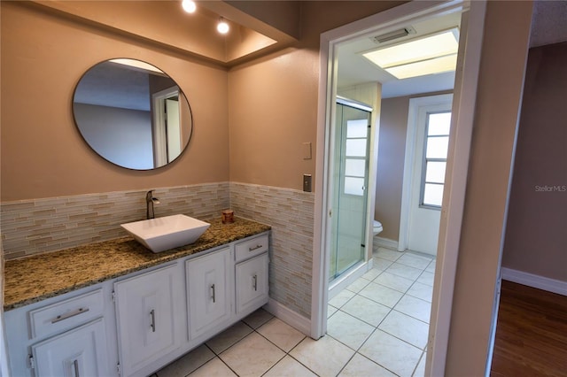 bathroom with toilet, an enclosed shower, tile walls, vanity, and tile patterned flooring