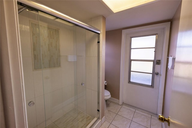 bathroom featuring tile patterned flooring, a shower with door, and toilet