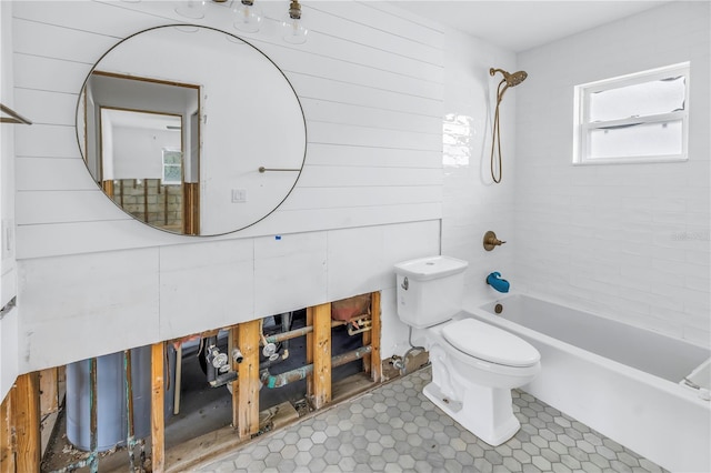 bathroom with wooden walls, tile patterned floors, toilet, and tiled shower / bath