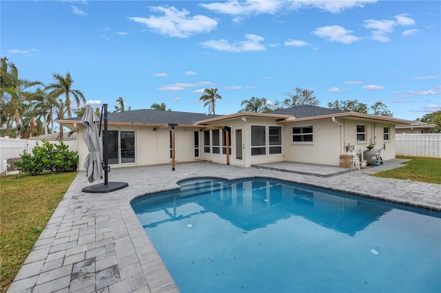 rear view of property featuring a fenced in pool, a patio area, and a sunroom