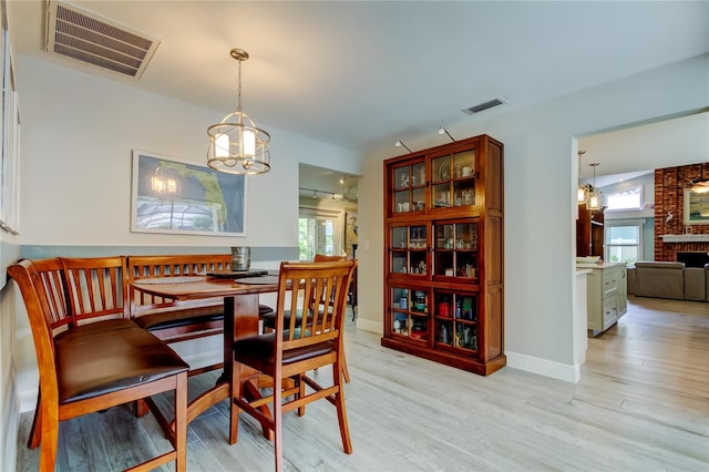 dining area with a brick fireplace and light wood-type flooring