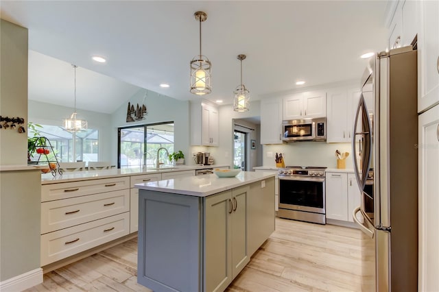 kitchen with stainless steel appliances, hanging light fixtures, a center island, and white cabinets