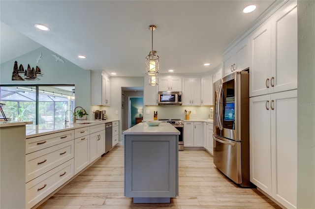 kitchen with sink, a center island, hanging light fixtures, stainless steel appliances, and white cabinets