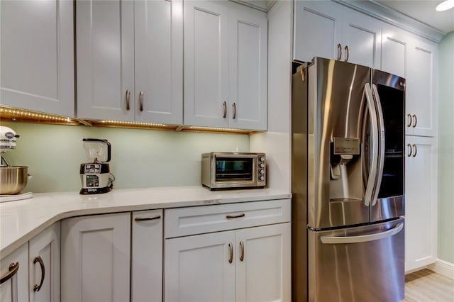 kitchen with white cabinets, stainless steel fridge, and light stone counters