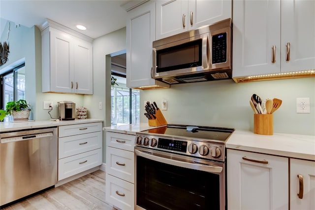 kitchen featuring stainless steel appliances, white cabinetry, light stone countertops, and light hardwood / wood-style flooring