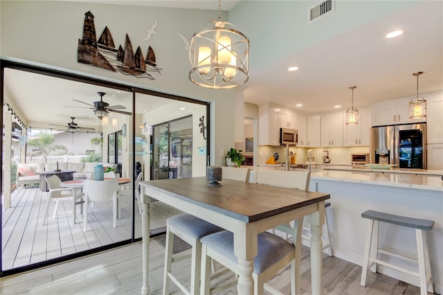 dining space featuring ceiling fan with notable chandelier and light wood-type flooring