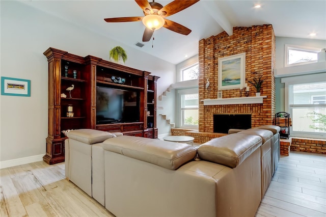 living room with ceiling fan, high vaulted ceiling, a fireplace, beamed ceiling, and light wood-type flooring