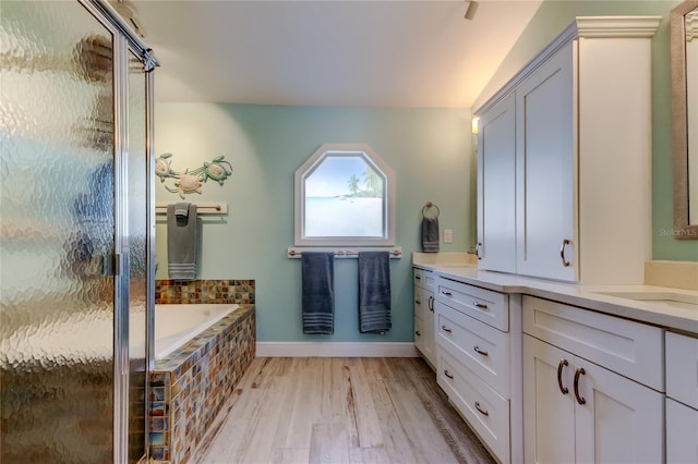 bathroom with hardwood / wood-style flooring, shower with separate bathtub, and vanity