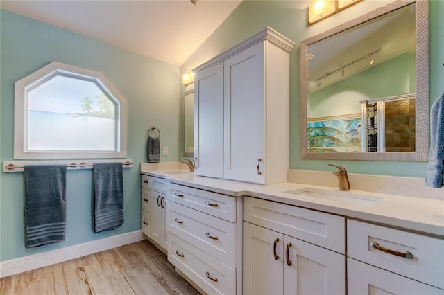 bathroom with rail lighting, a shower, vaulted ceiling, vanity, and hardwood / wood-style floors