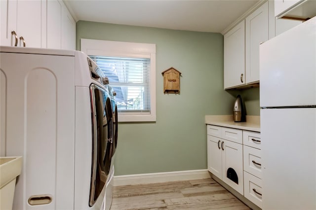 laundry area with cabinets, washer and dryer, and light hardwood / wood-style floors