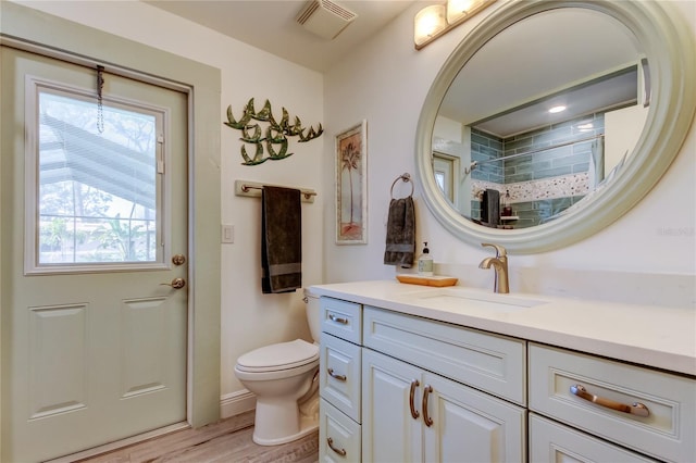 bathroom featuring vanity, hardwood / wood-style flooring, a shower, and toilet