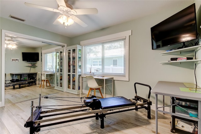 workout room with hardwood / wood-style floors, a healthy amount of sunlight, and ceiling fan