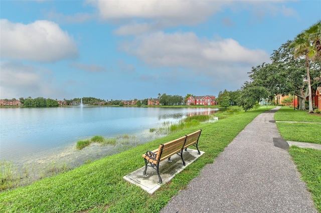 view of property's community with a water view and a lawn