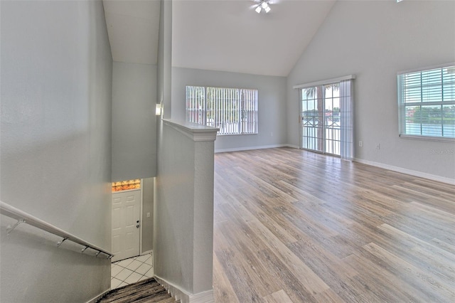 unfurnished living room featuring high vaulted ceiling and light hardwood / wood-style flooring