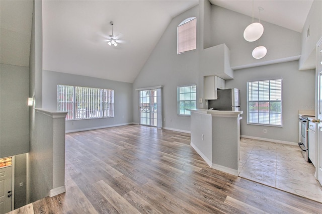 unfurnished living room featuring a wealth of natural light, light hardwood / wood-style flooring, high vaulted ceiling, and ceiling fan