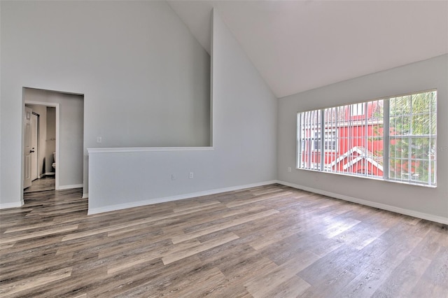 spare room featuring high vaulted ceiling and hardwood / wood-style floors