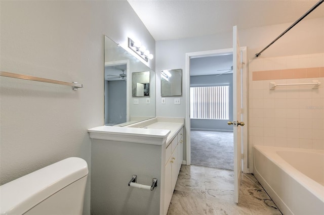 full bathroom featuring ceiling fan, vanity, toilet, and tiled shower / bath combo