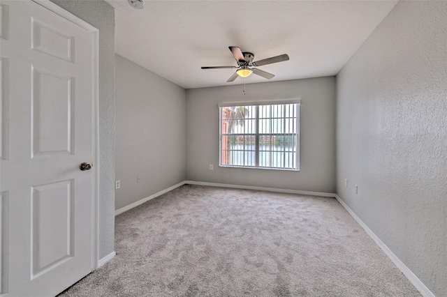 spare room featuring light colored carpet and ceiling fan