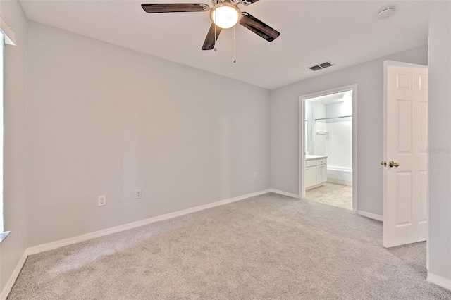 unfurnished bedroom with ensuite bathroom, light colored carpet, and ceiling fan