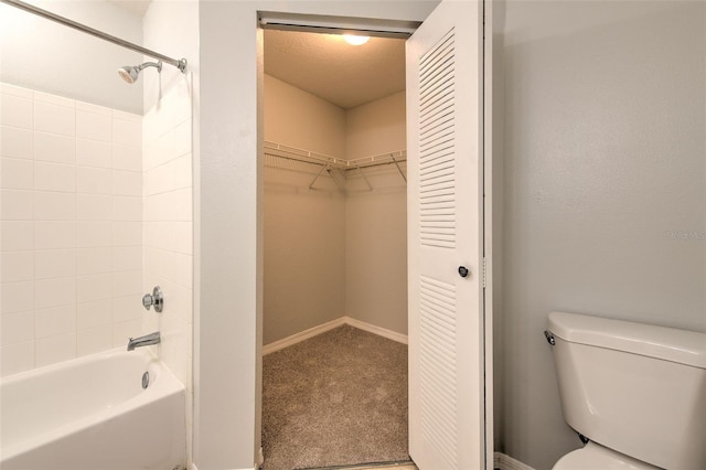 bathroom featuring tiled shower / bath, a textured ceiling, and toilet