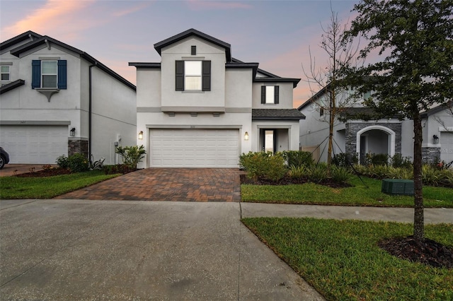 view of front facade featuring a garage, decorative driveway, and stucco siding