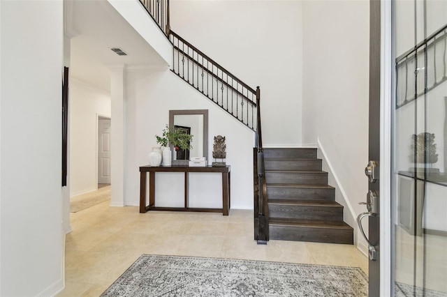 staircase featuring visible vents, tile patterned flooring, a towering ceiling, and baseboards