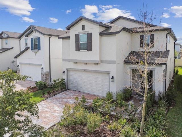 view of front of house with decorative driveway, an attached garage, and stucco siding